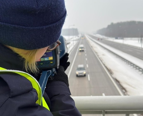 Policjantka ruchu drogowego rejestrująca prędkość pojazdów w trakcie zajęć praktycznych.