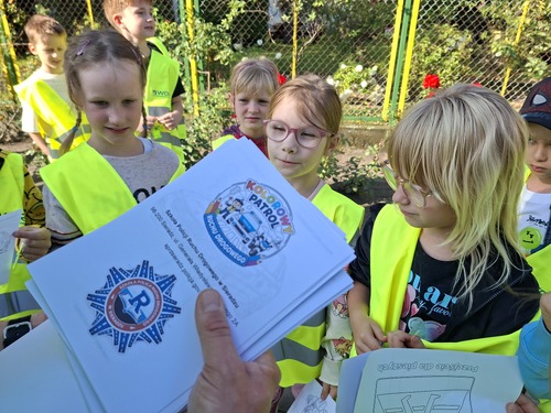 Na zdjęciu widoczny moment rozdawania przez policjantów kolorowanek dla dzieci